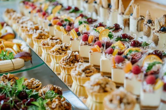 Rows of assorted dessert parfaits and fruit-topped pastries on a buffet table Rows of assorted dessert parfaits and fruit-topped pastries on a buffet table