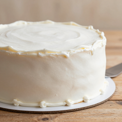 Baker rolling fondant over a tiered cake