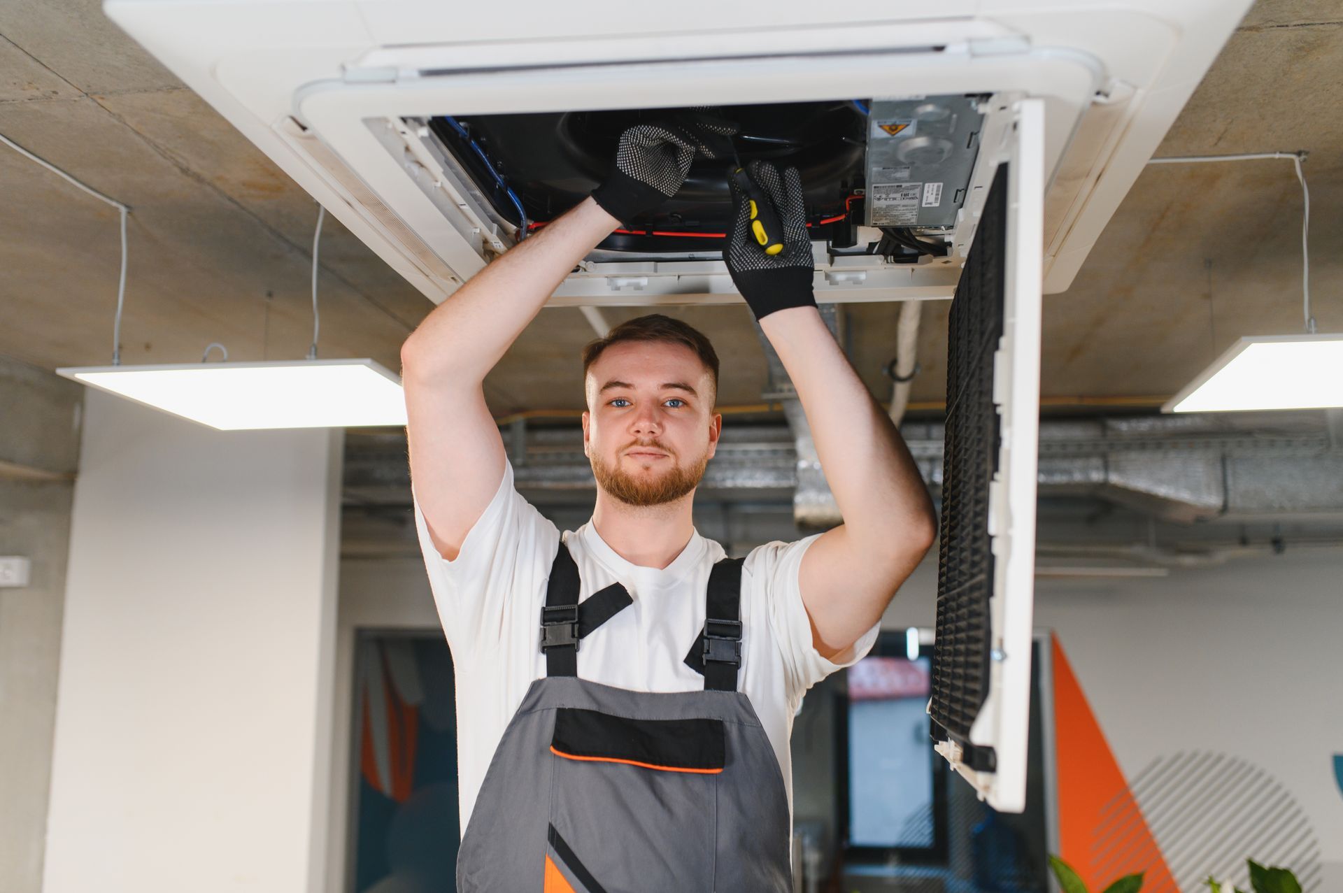 HVAC technician repairing ceiling air conditioning unit. HVAC technician repairing ceiling air conditioning unit.
