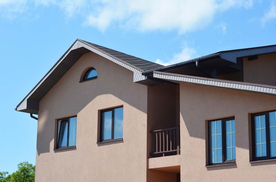 A house with a balcony and a blue sky in the background