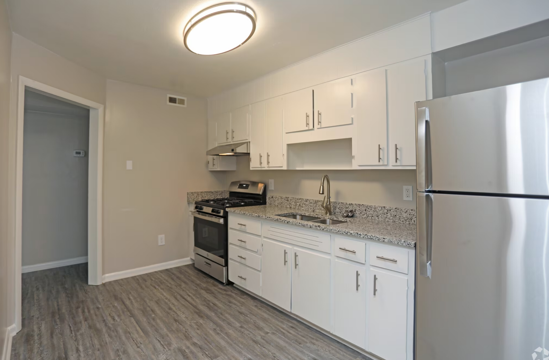 A kitchen with white cabinets , stainless steel appliances , and a refrigerator.