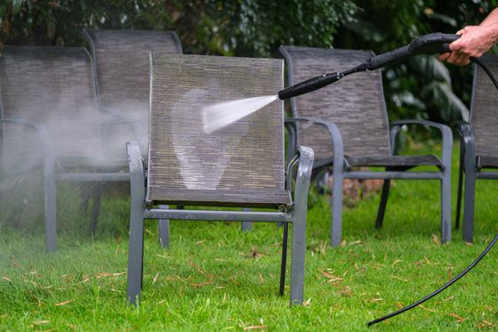 A person is cleaning a chair with a high pressure washer