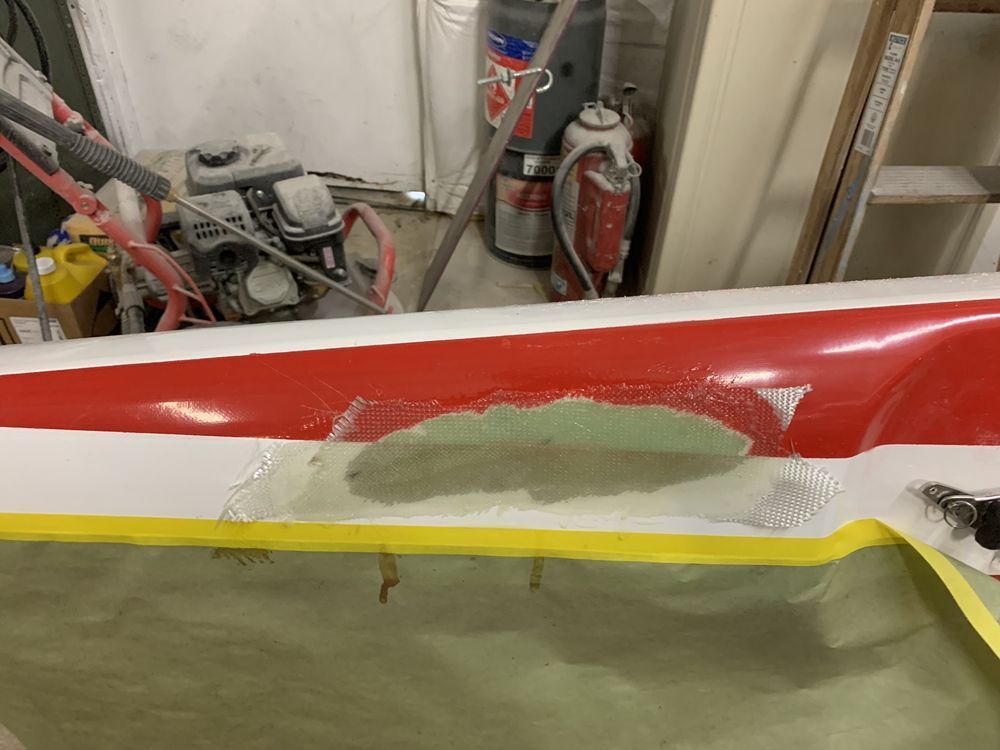 A red and white boat is being repaired in a garage