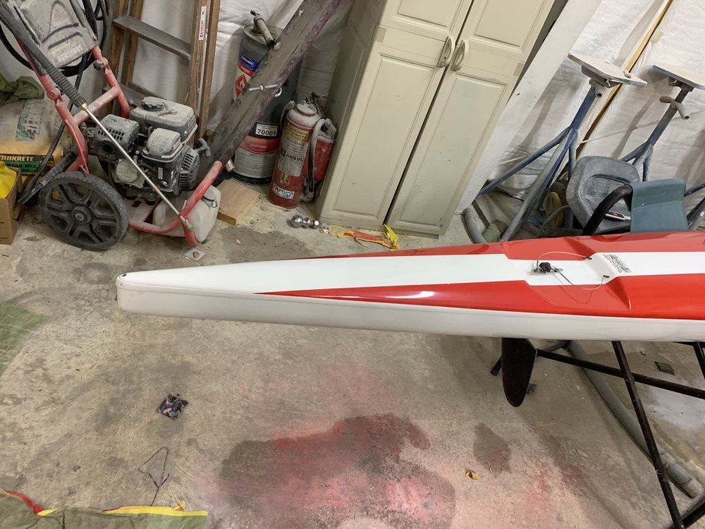 A red and white kayak is sitting on a table in a garage.