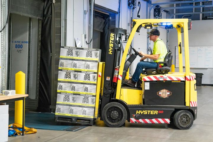Yellow Hyster forklift loading stacked boxes at a warehouse dock