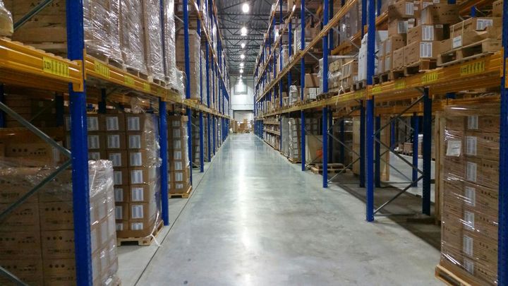 Long warehouse aisle with stacked boxes on tall metal shelves