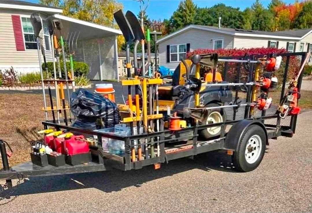 Utility trailer loaded with lawn equipment and tools parked on a residential street