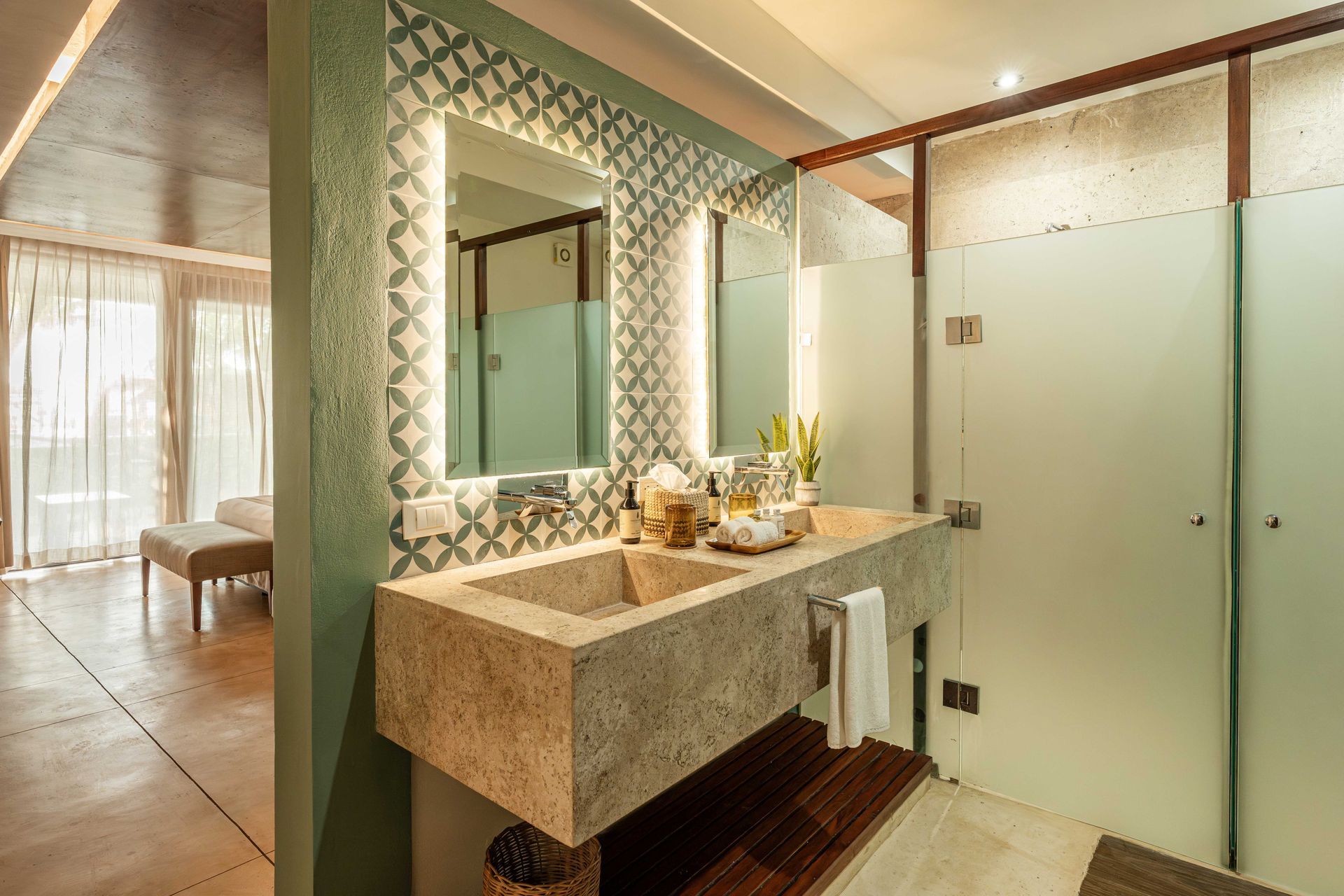 Bathroom with stone sink, ornate backsplash, backlit mirror, and frosted glass shower.