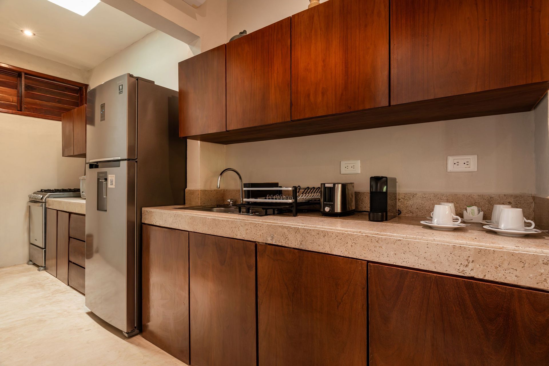 Modern kitchen with wood cabinets, stainless steel appliances, and beige countertop.