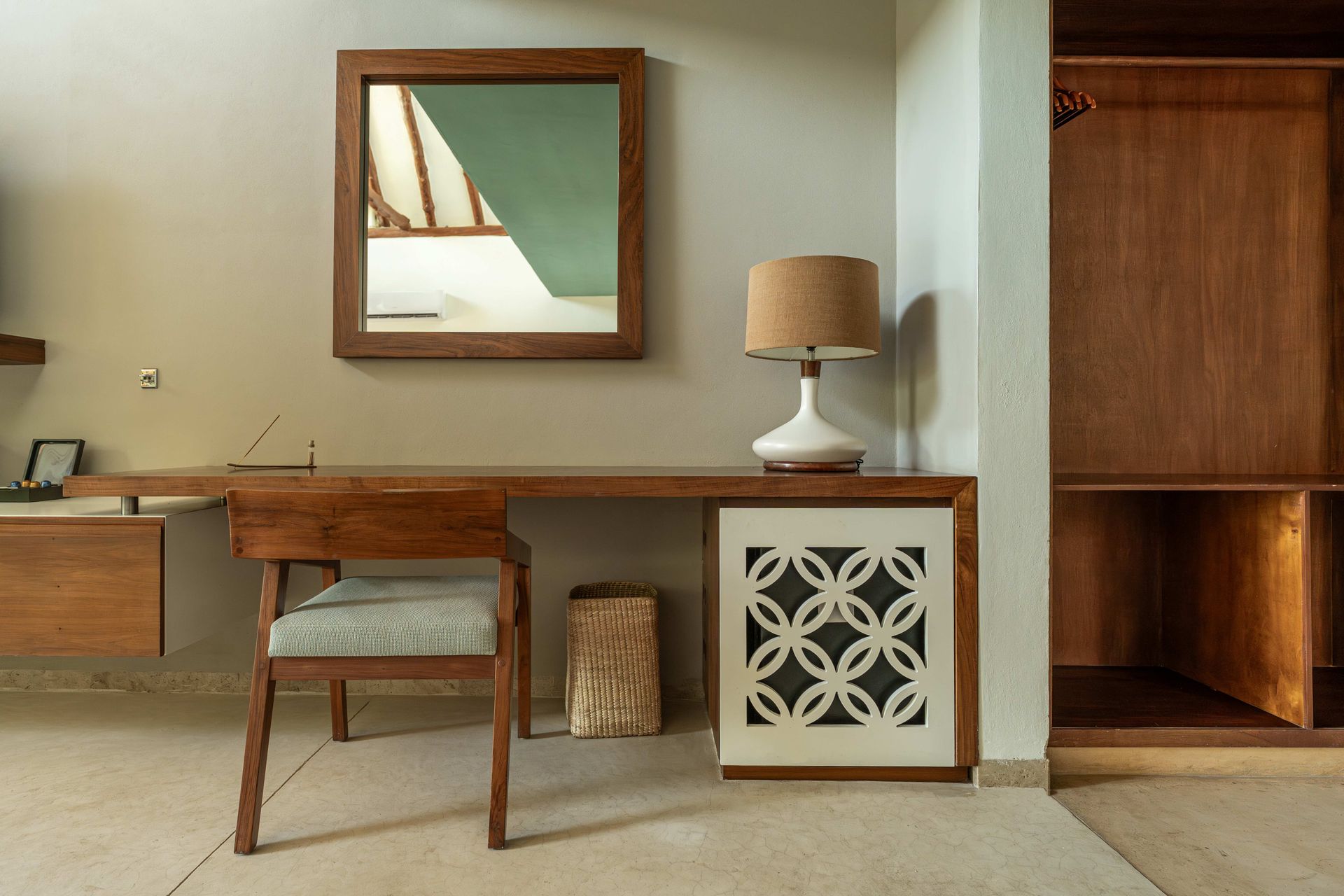 Wooden desk and chair in room with mirror, lamp, and cabinet.