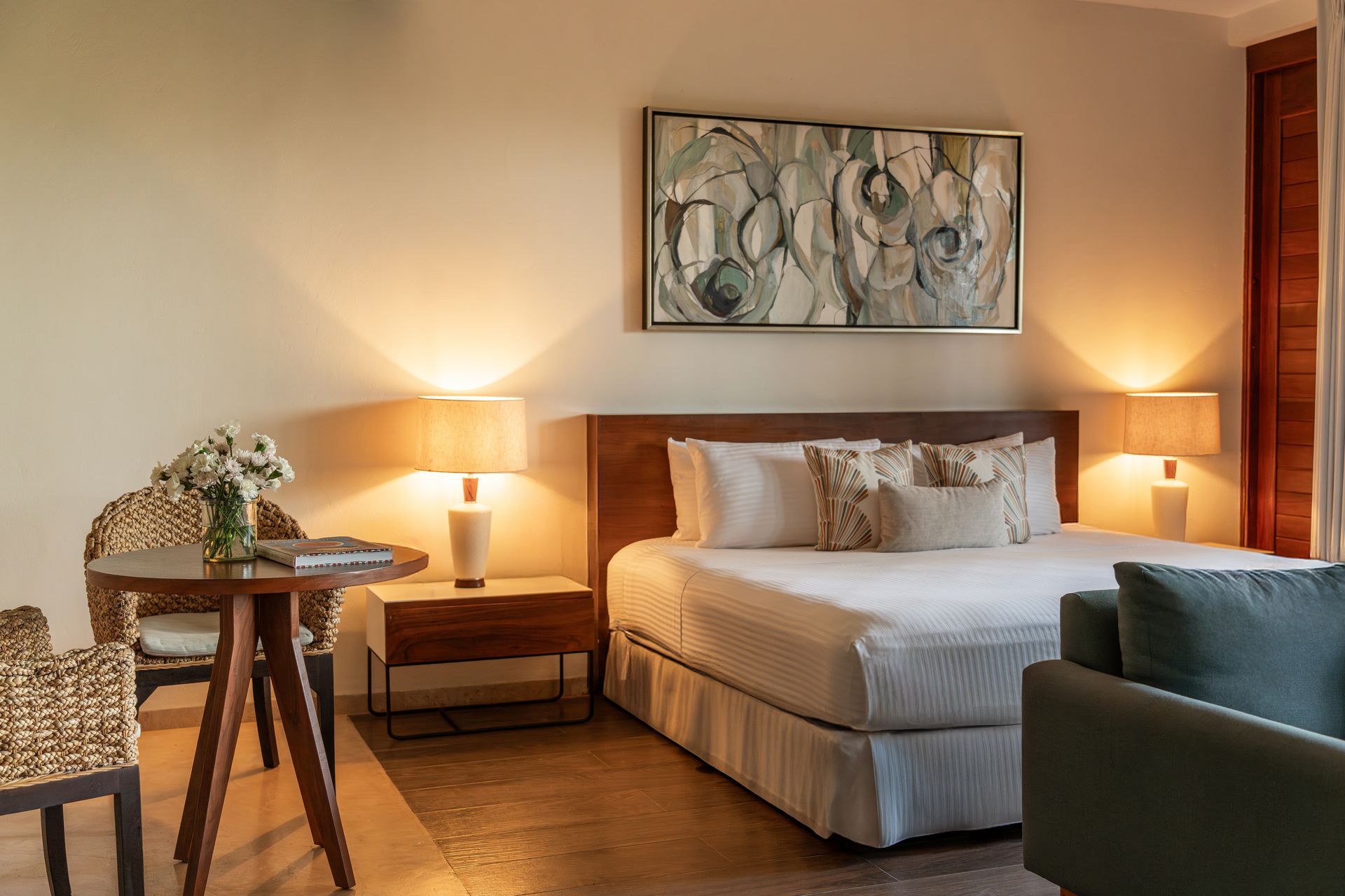 Bedroom with a bed, nightstands, chair, and a table. A painting hangs above the bed.