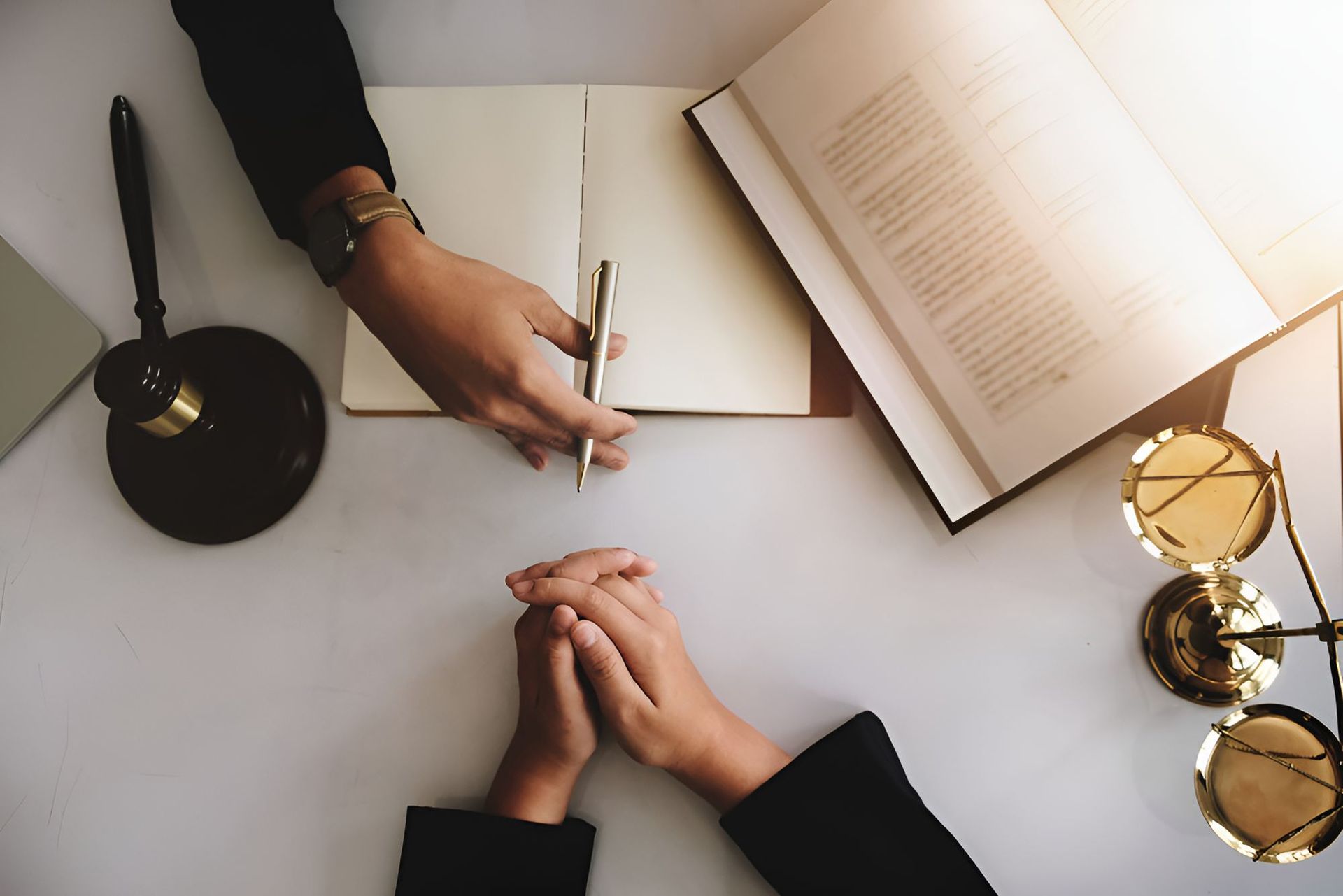 A Person Is Sitting At A Table With A Pen And A Book — North Coast Conveyancing In Port Macquarie, NSW