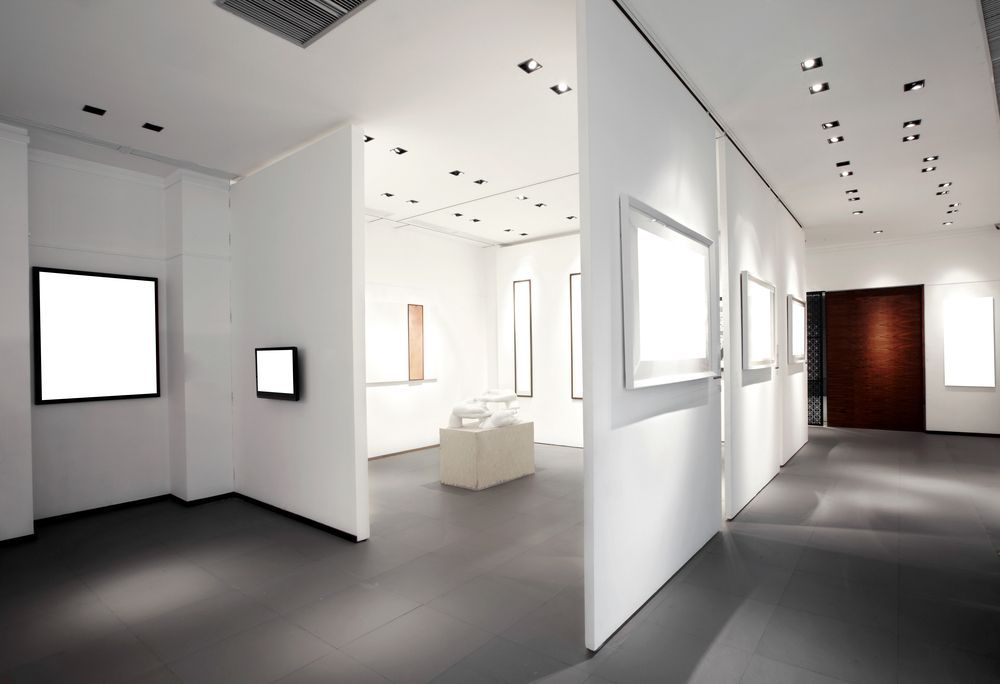 Minimalist white art gallery with framed wall pieces and gray floors