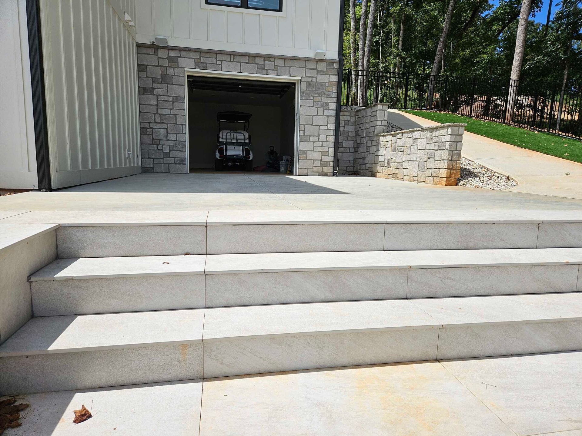 Concrete steps leading up to a garage with stone accents. A golf cart is parked inside.