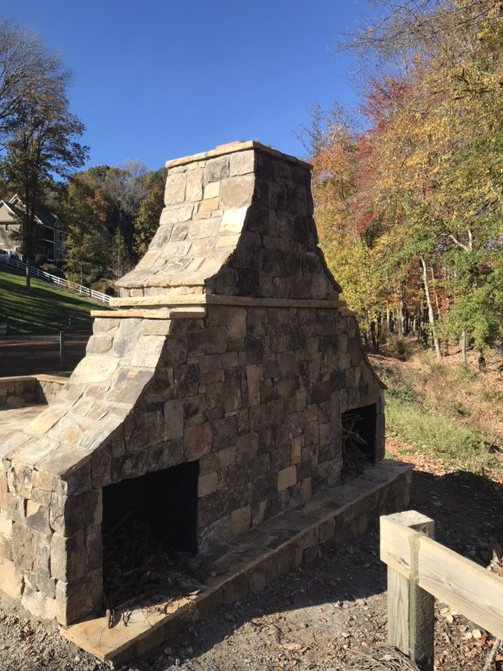 Stone patio with steps, pergola, and brick apartment building with arched entryways