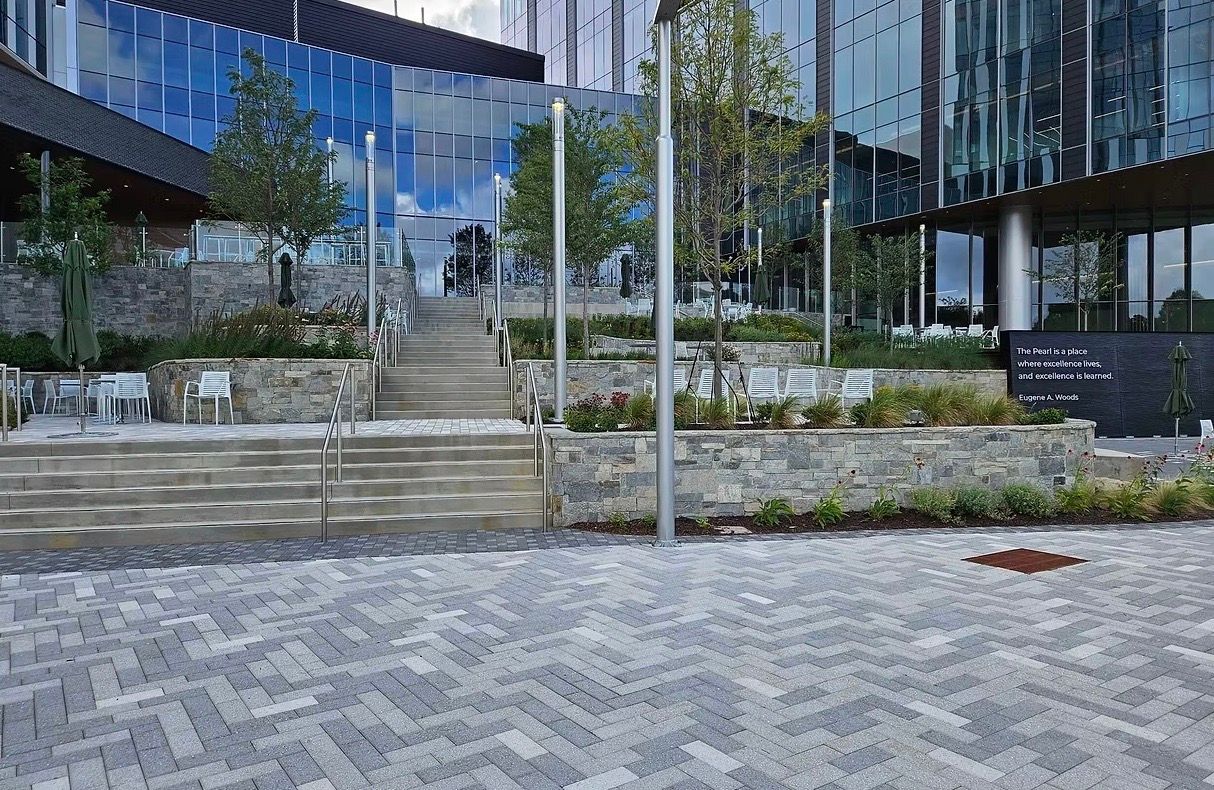Stone patio with steps, pergola, and brick apartment building with arched entryways