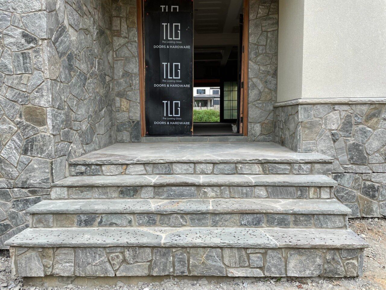 Stone patio with steps, pergola, and brick apartment building with arched entryways