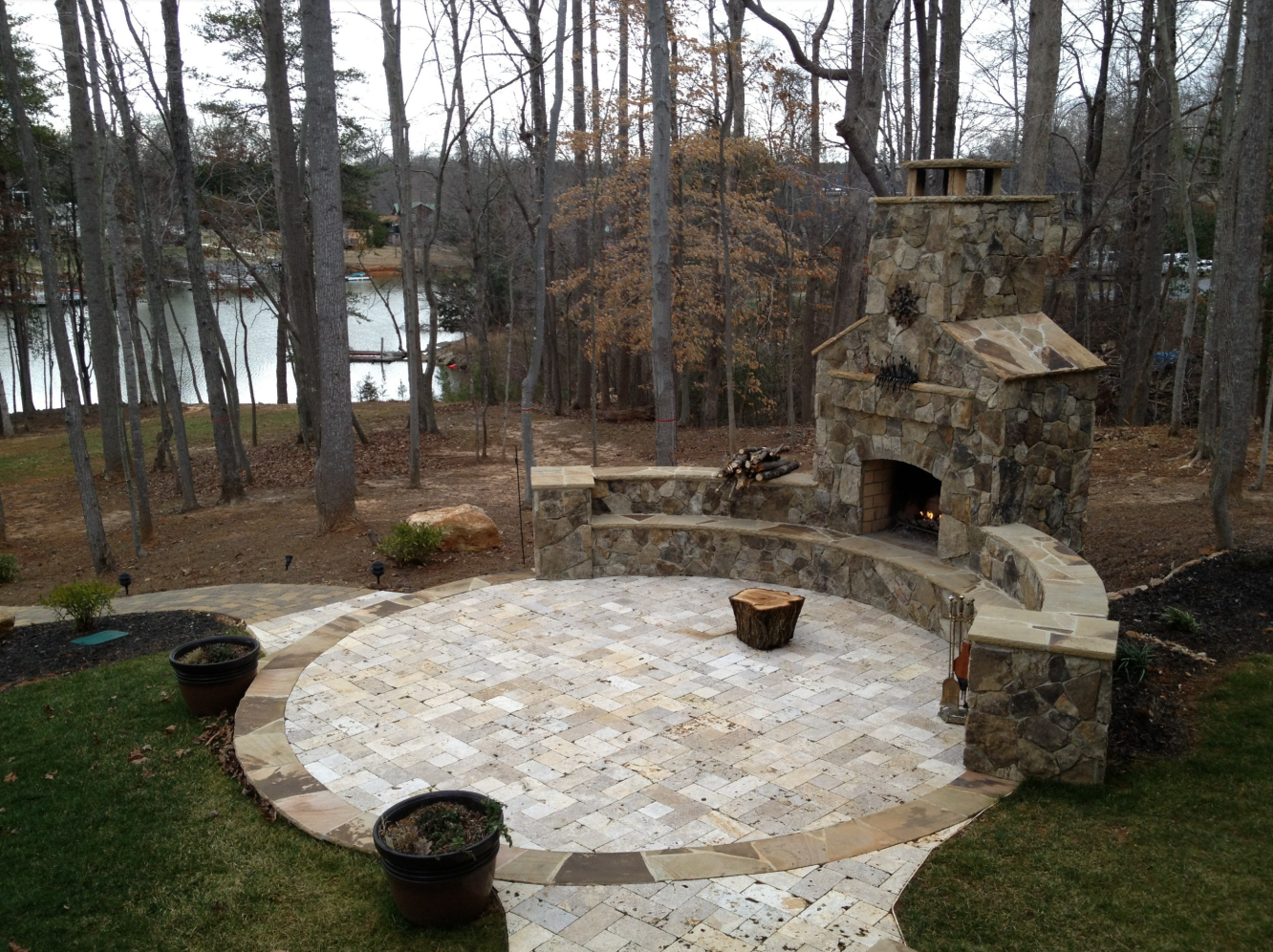 Stone patio with fireplace overlooking a lake.