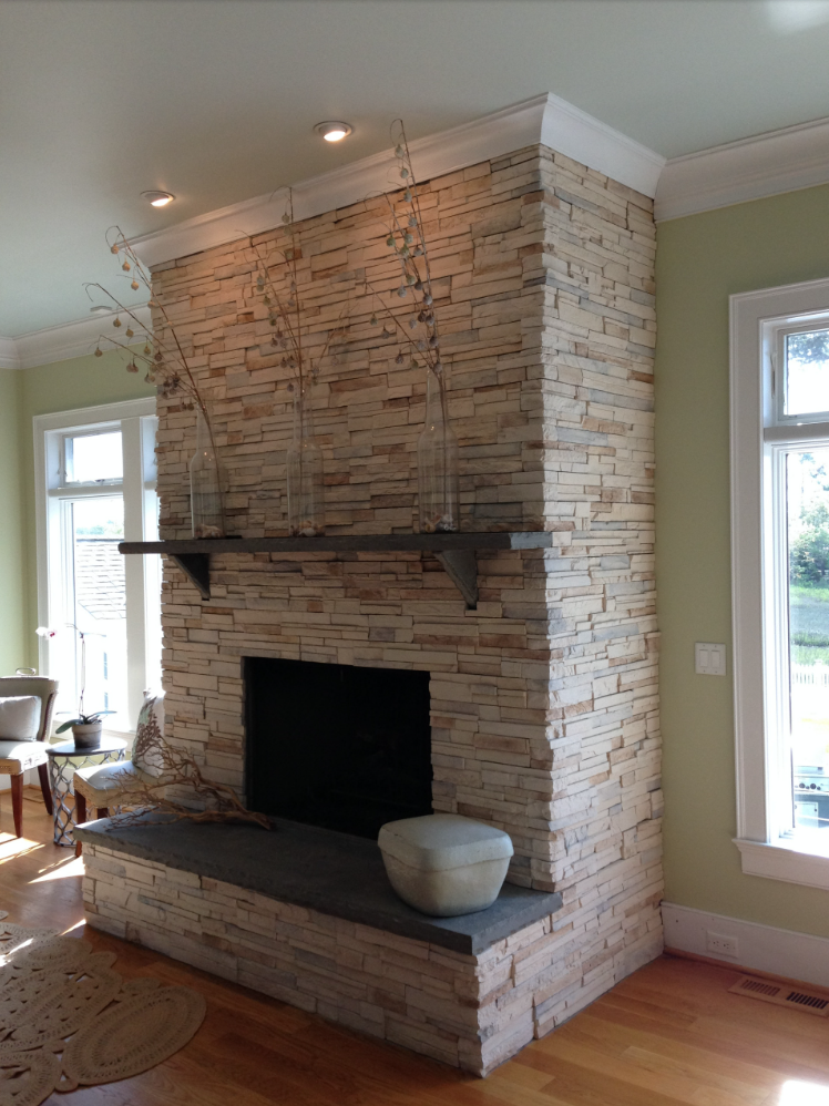 Stone fireplace with dark hearth and mantel, neutral walls, and a light-colored stone facade.