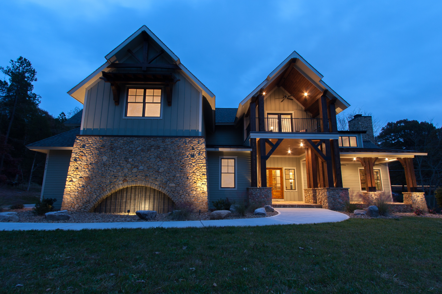 A rustic house with stone accents and wooden beams illuminated at dusk.