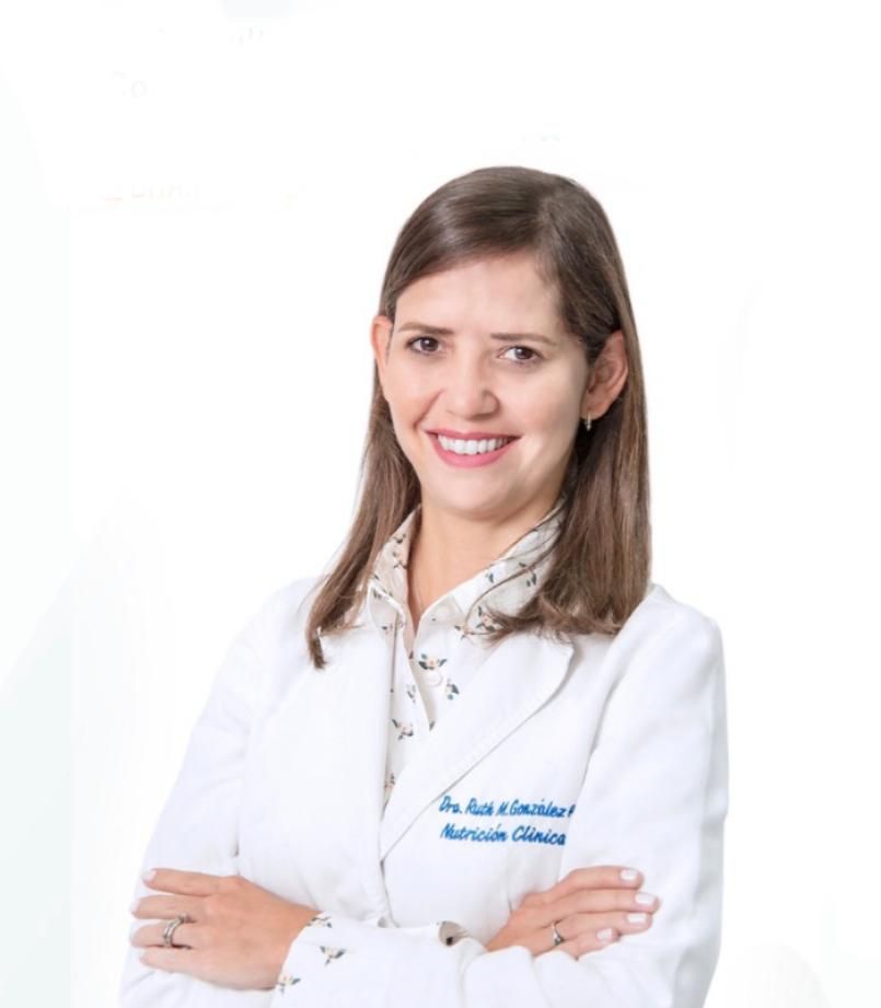 A woman in a white lab coat is smiling with her arms crossed
