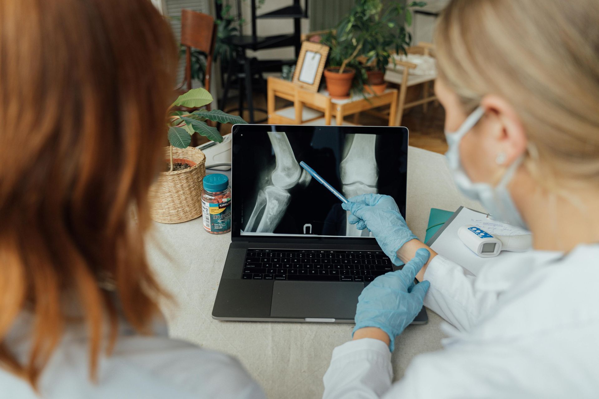 Two doctors are looking at an x-ray of a knee on a laptop.