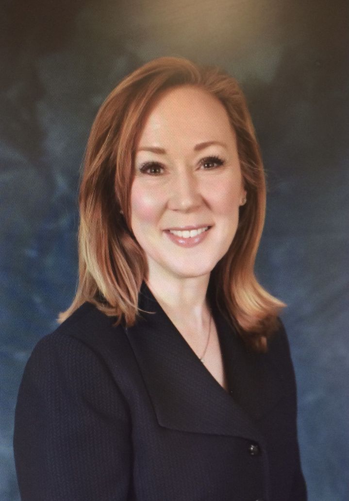 A woman in a black suit is smiling for the camera.