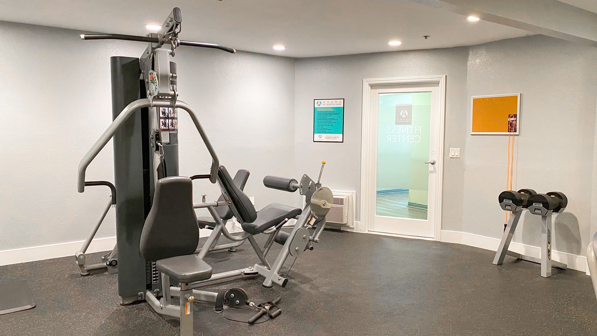 a gym with a lot of equipment and a door .