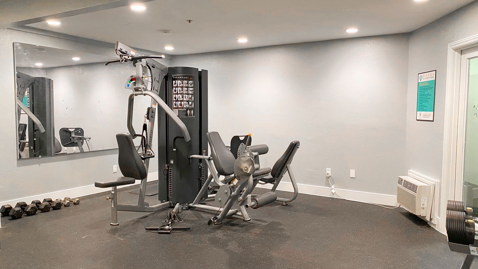 a gym with a lot of equipment and a large mirror .