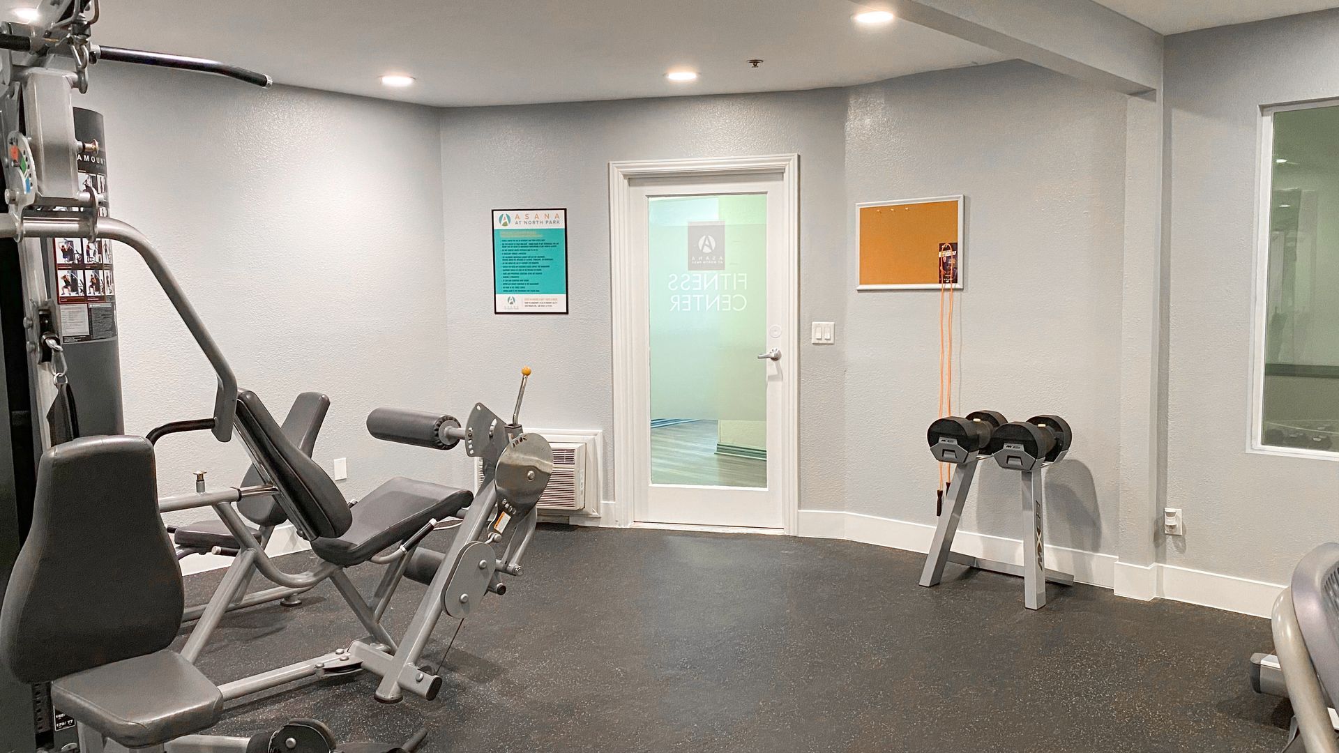 a gym with a lot of equipment and a door .