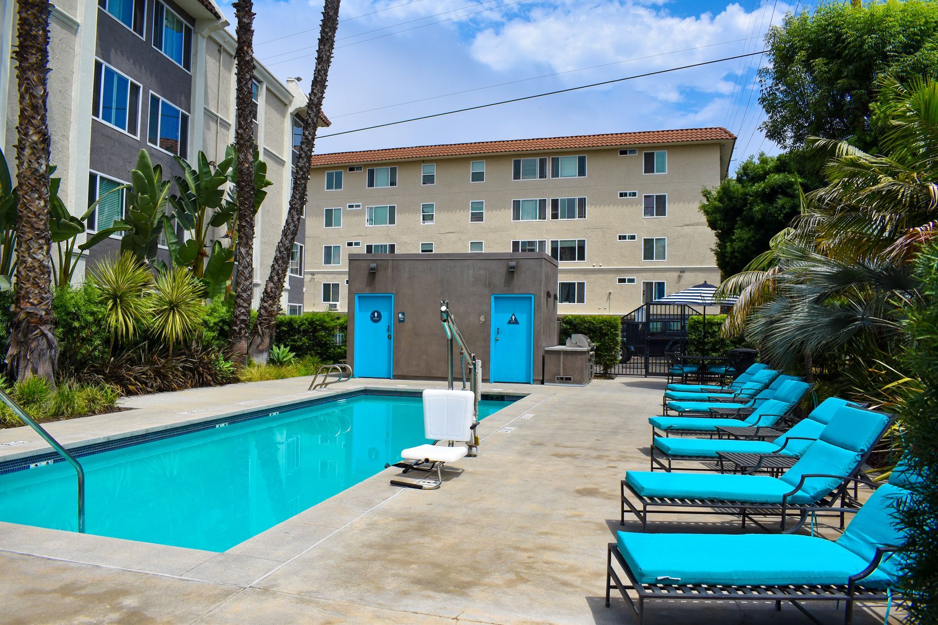 a swimming pool with blue chairs and a building in the background
