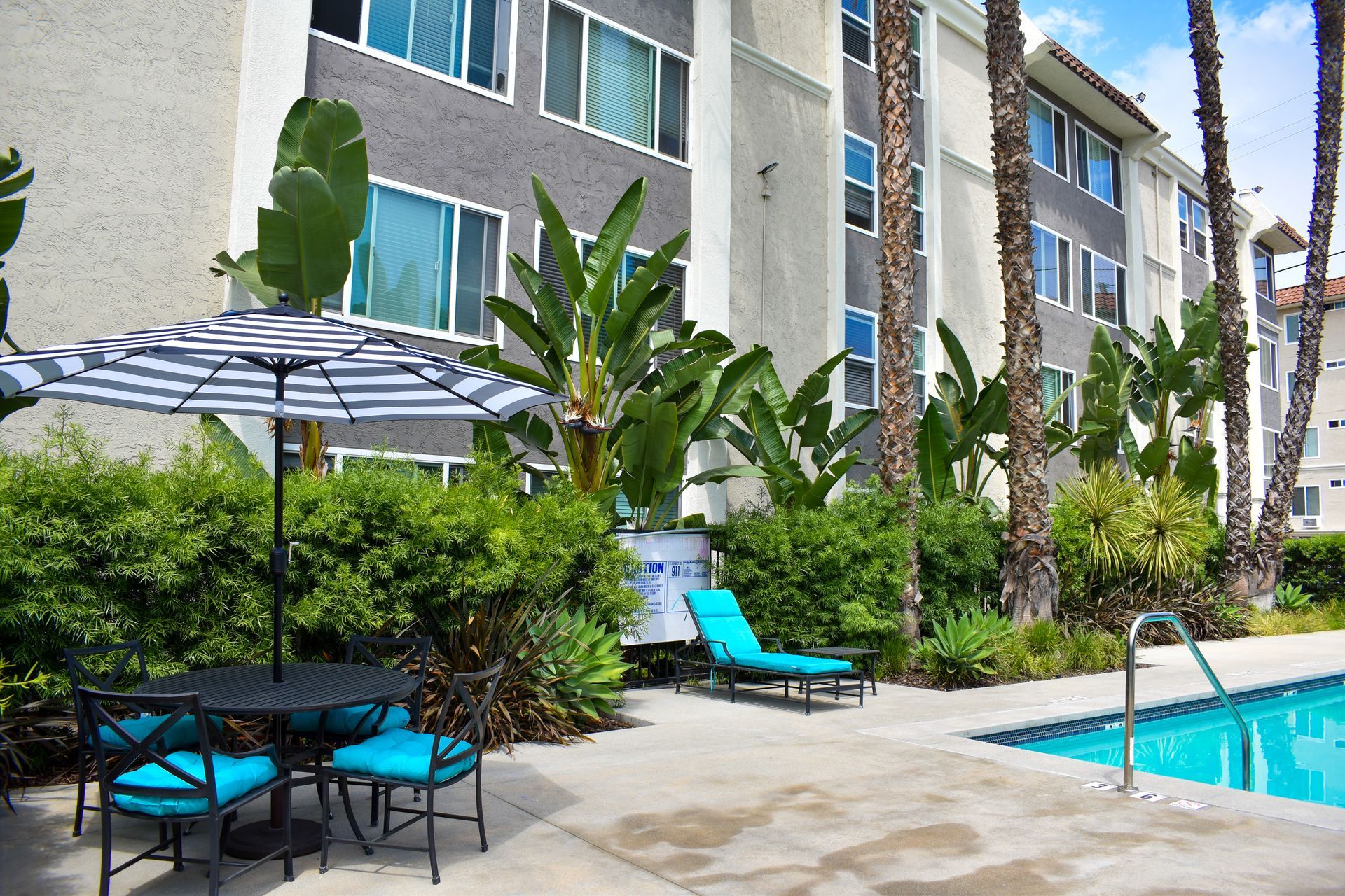 a swimming pool with a table and chairs in front of a building