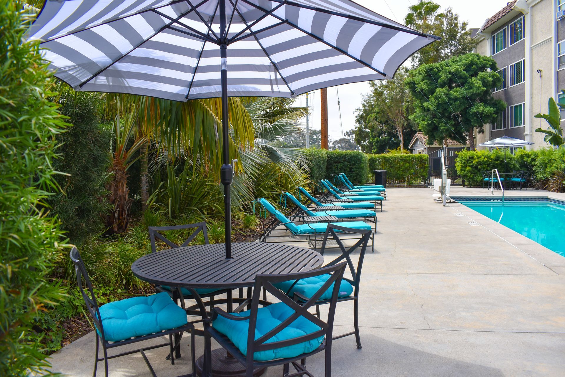 a table and chairs under an umbrella next to a pool