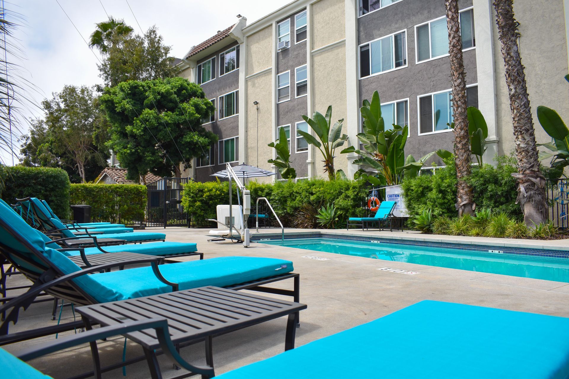 a swimming pool with blue lounge chairs in front of a building .