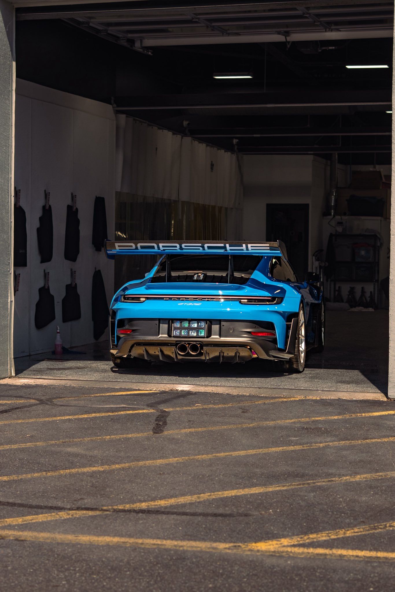 Blue sports car parked in a dim garage with a large rear wing