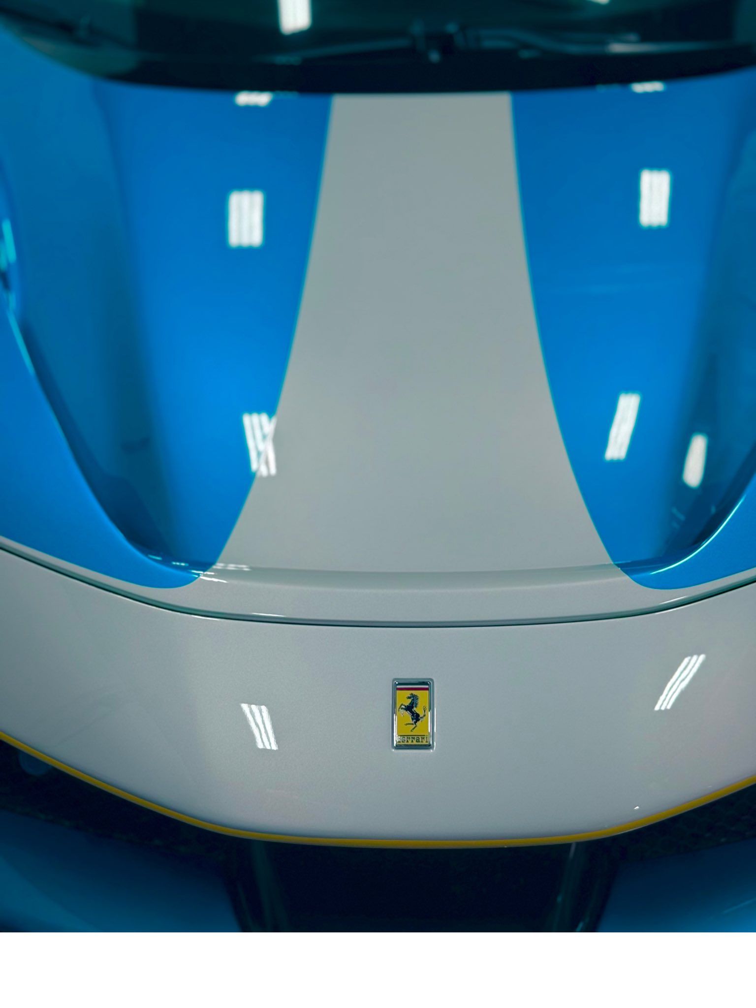 Close-up of a blue and white Ferrari front hood with the prancing horse emblem