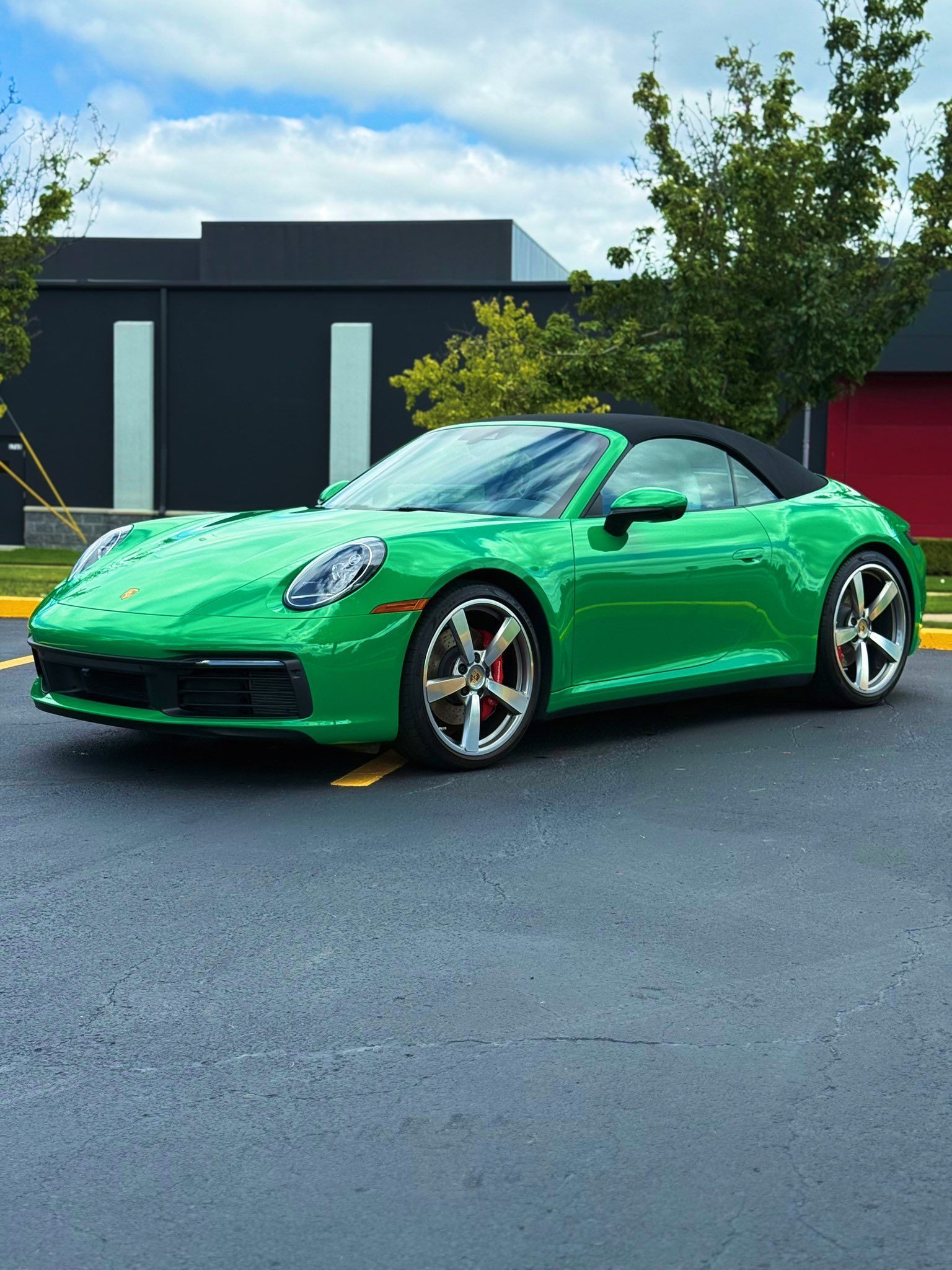 Bright green sports car parked on pavement in front of a modern house and trees