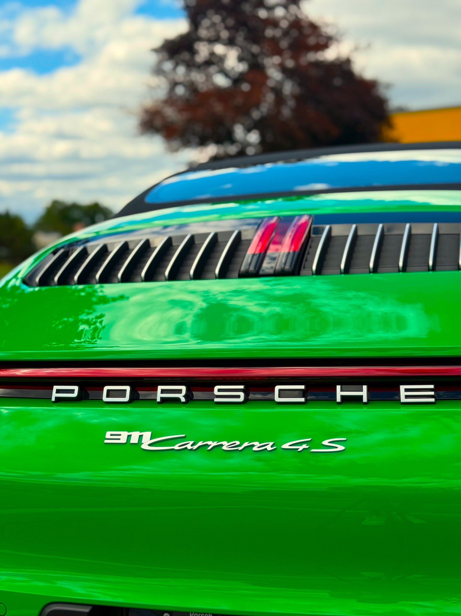 Rear of a bright green Porsche 911 Carrera 4S with black rear vents and red taillights