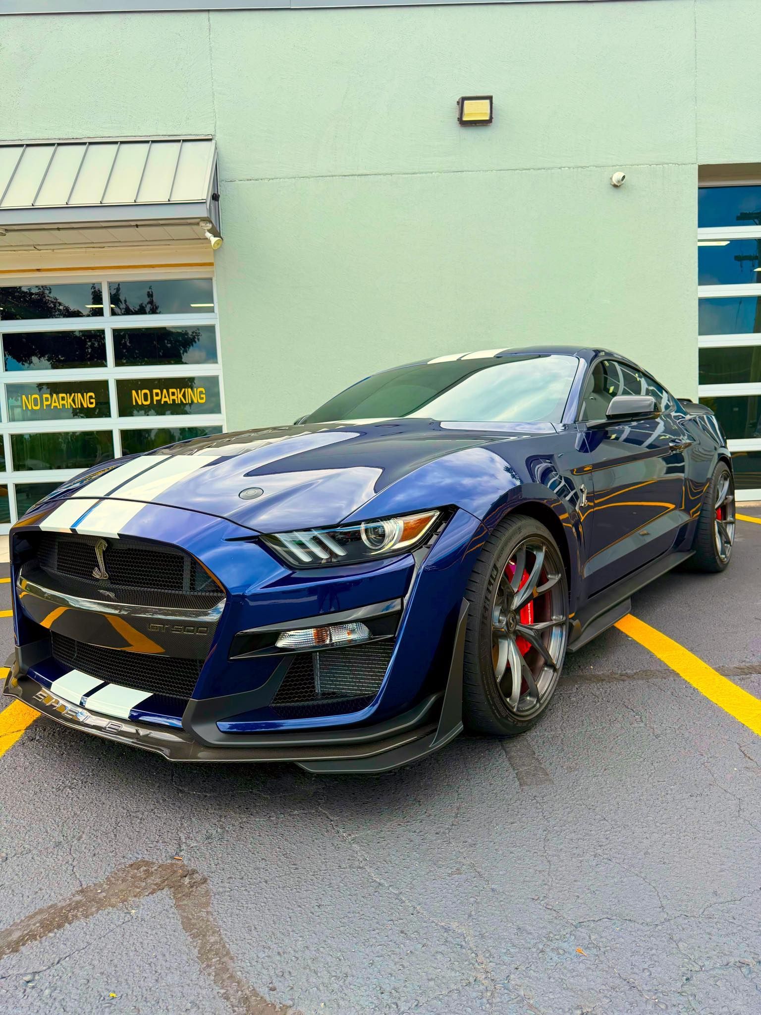 Blue sports coupe parked outside a building, angled in a parking lot with yellow lines.