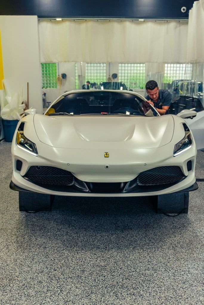 White sports car in a showroom with a person leaning over the passenger side.