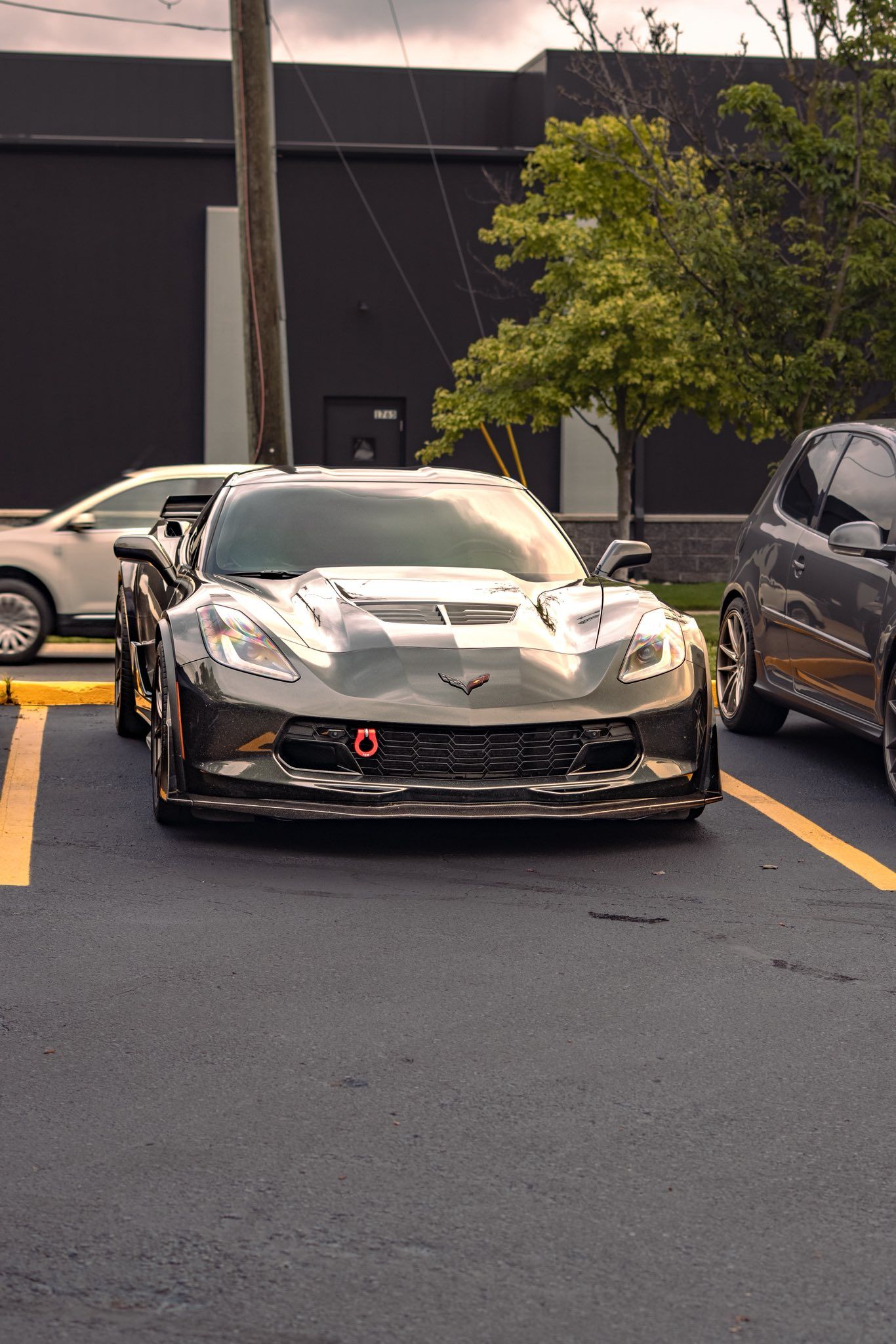 Camouflaged sports car parked in a lot, front view beside other vehicles.
