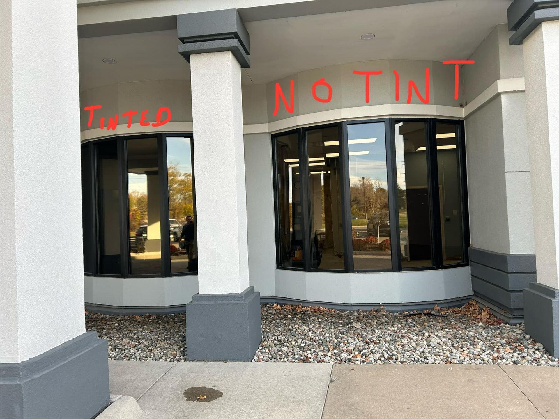 Storefront with large windows and red graffiti reading “TINTED” and “NOTINT” above the entrance