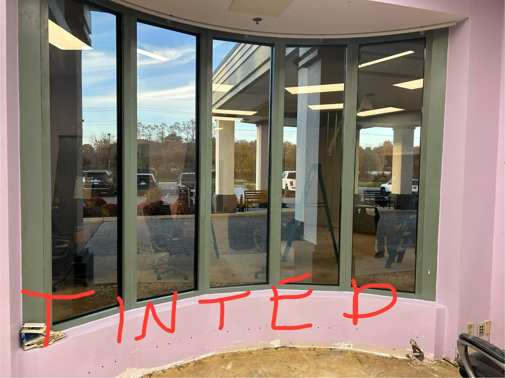 Curved glass entrance with pink walls and red “INTED” marking across the lower windows