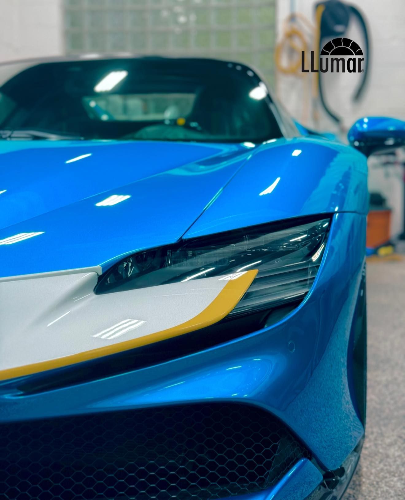 Blue sports car front end with sleek headlight in an indoor garage or showroom