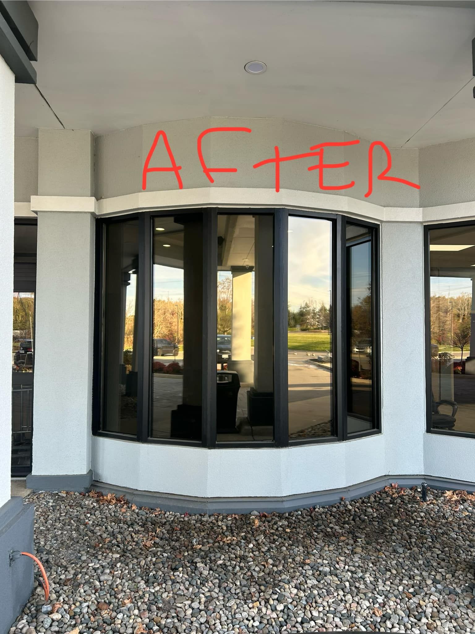 Covered building entrance with dark windowed vestibule and gravel foreground, red graffiti reading “AFTER” above.