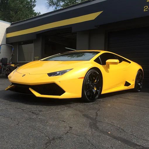 Yellow Lamborghini parked outside a garage, angled on wet pavement