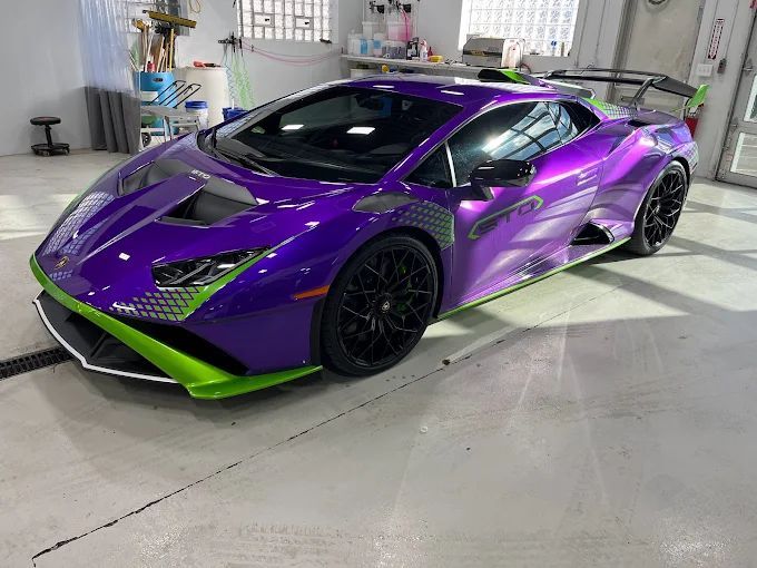 Purple and neon green Lamborghini in a garage, shown in three-quarter front view.