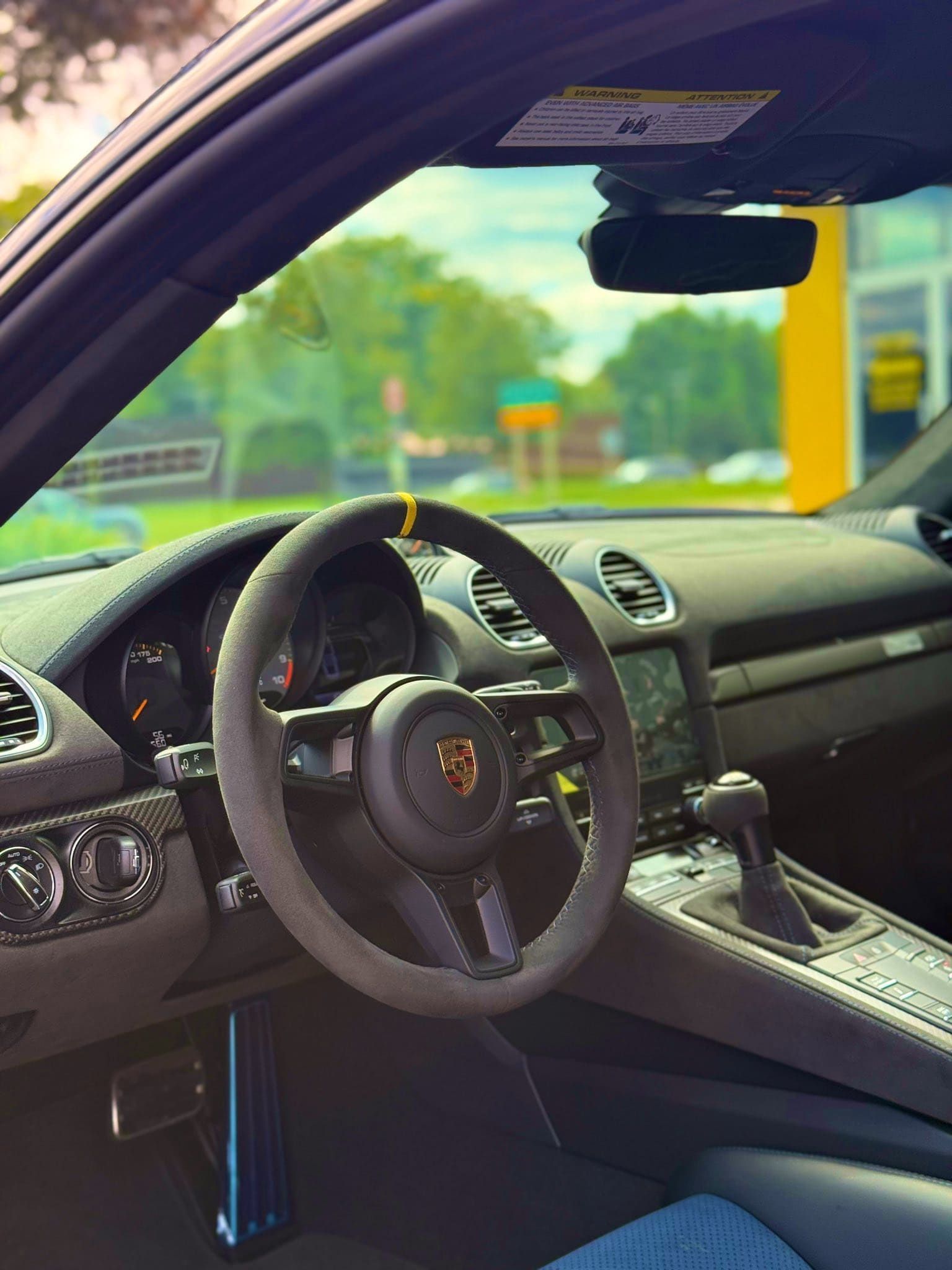 Car interior with steering wheel, dashboard, and center console, viewed from the driver’s side.