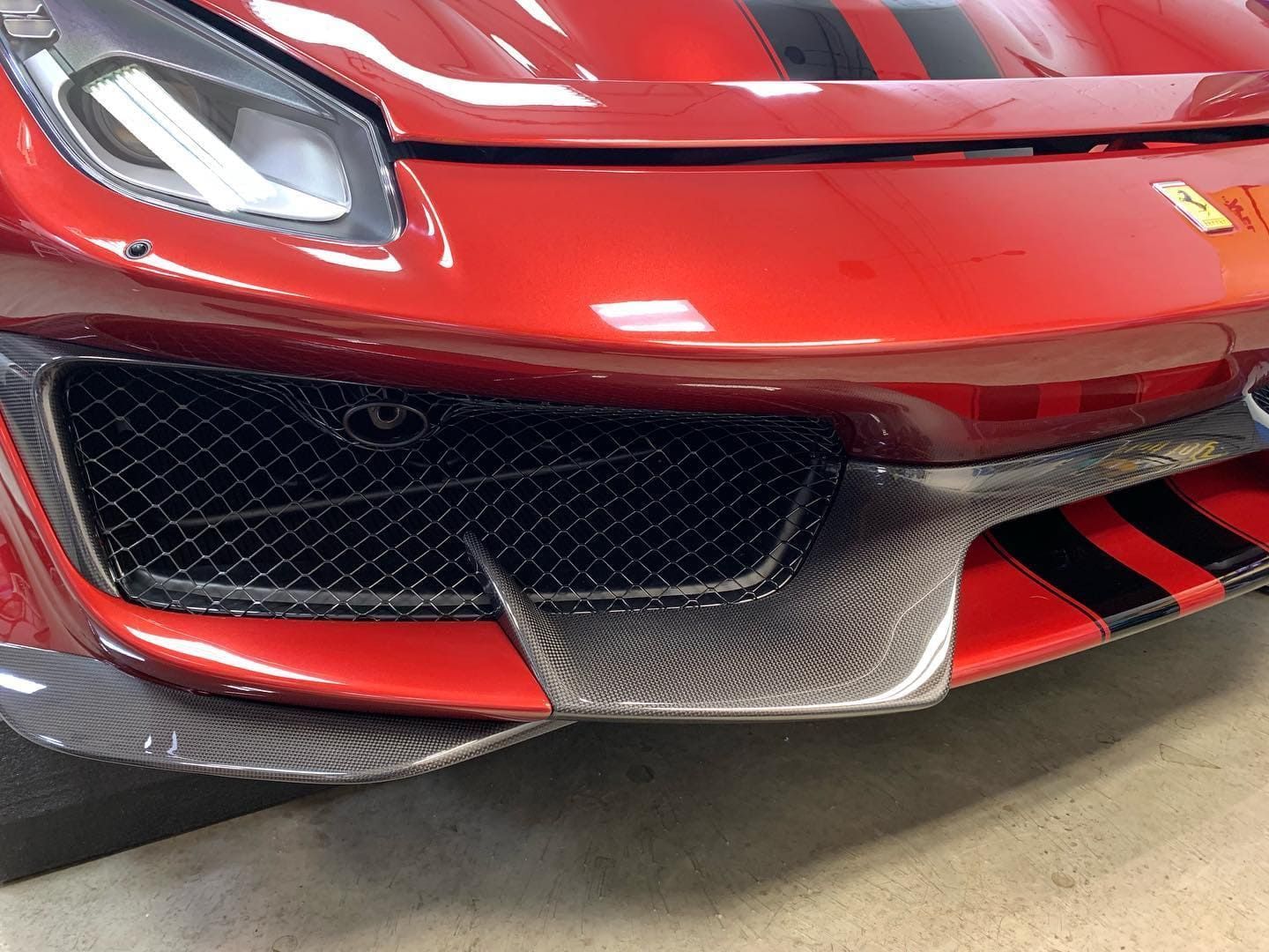 Front end of a red sports car with black grille and silver accents