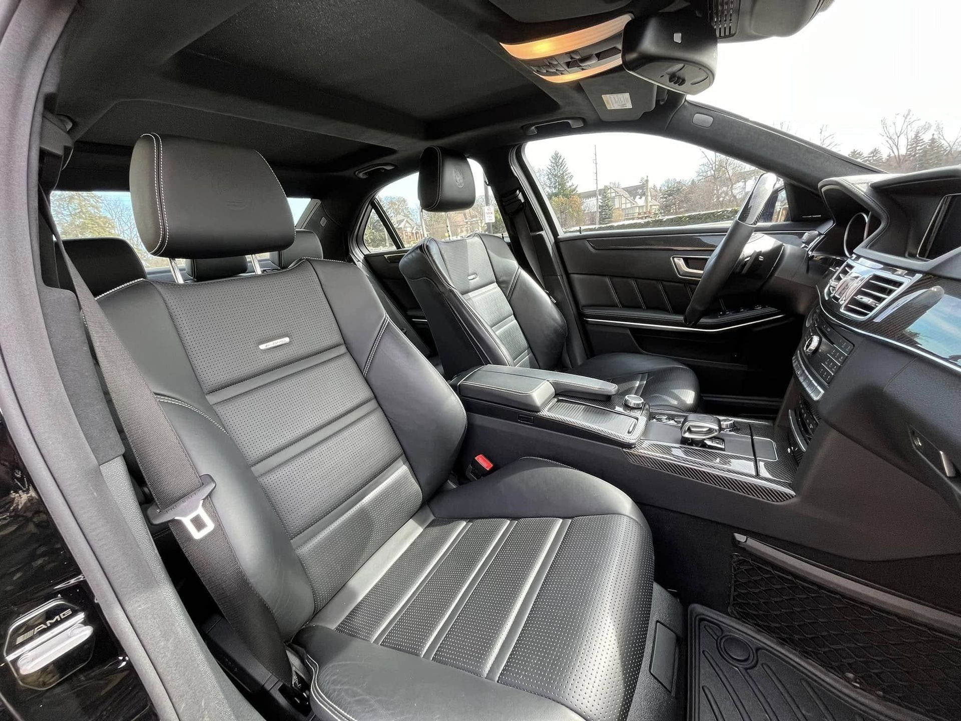 Luxury car interior with black leather seats and a panoramic sunroof from the front passenger side